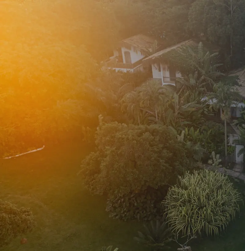 Vista aérea das casas da Bahia Bonita no meio da mata, com luz dourada do fim de tarde