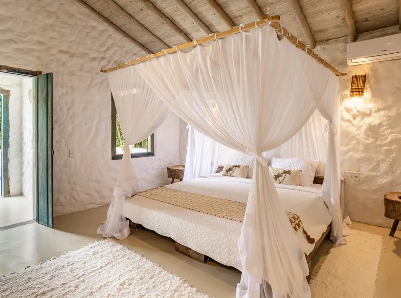 Quarto com cama de dossel e paredes brancas de pedra