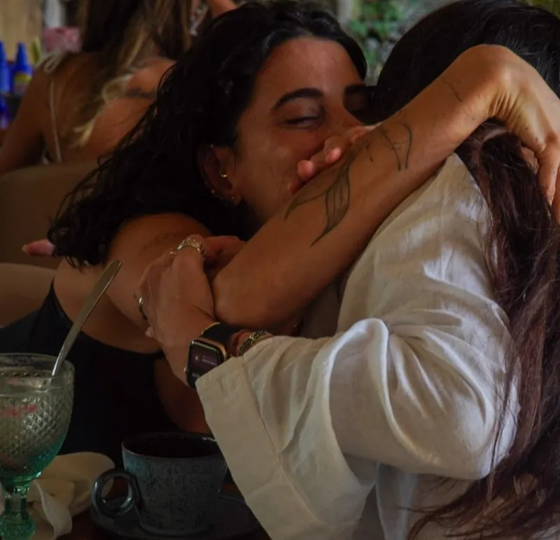 Duas participantes em um abraço apertado à mesa