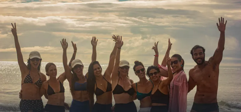 Participantes da edição de março de 2026 com os braços erguidos na praia