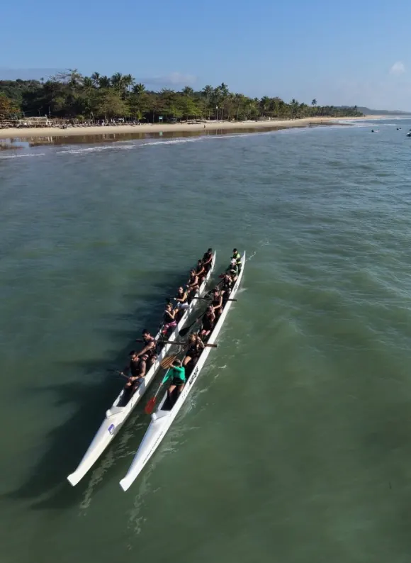 Duas canoas havaianas remando em águas verdes