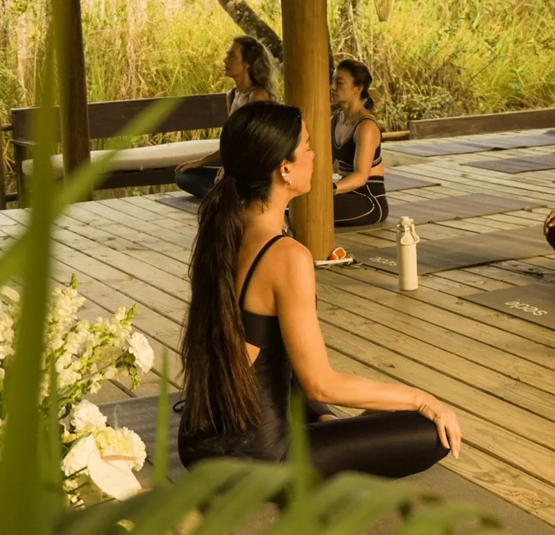 Prática de yoga no deck de madeira cercado de verde